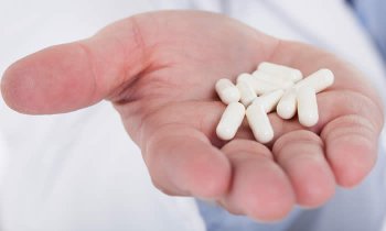 La mano di un medico offre al paziente capsule a base di glucosamina e condroitina per la gestione del dolore articolare associato all'artrosi